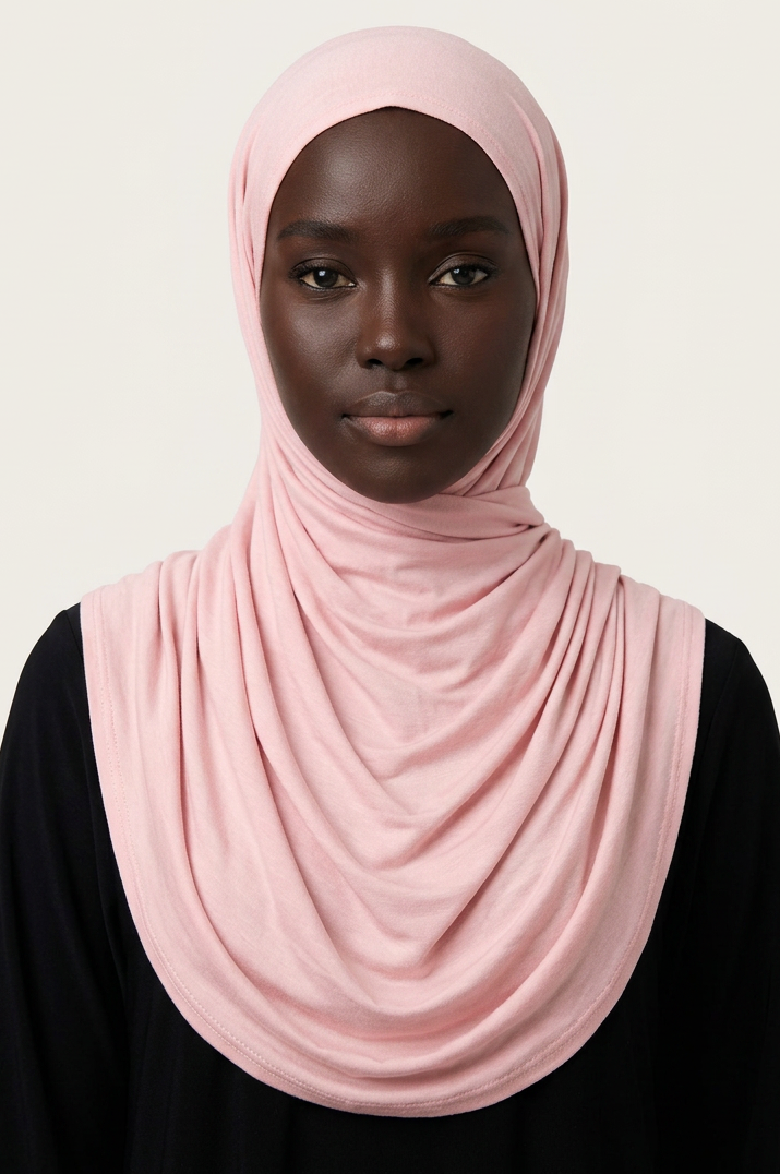 Person wearing a pink hijab against a plain background