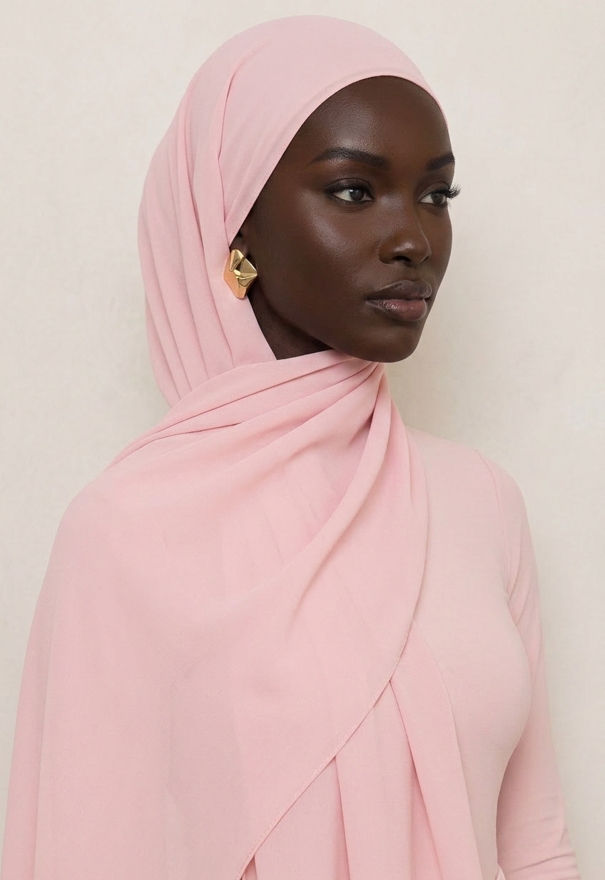 Woman wearing a pink hijab against a plain background